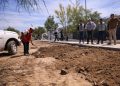 Construction Worker in a Red Safety Vest Shovels Dirt Beside a White Pickup While Five Colleagues Watch from the Sidewalk. - Hola Mty